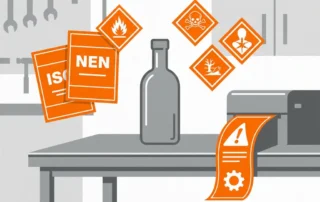 Kleine glazen decanteerflacon op stalen werkvlak, omringd door GHS-gevaarsymbolen en chemische waarschuwingsetiketten in signaaloranje en grijs.